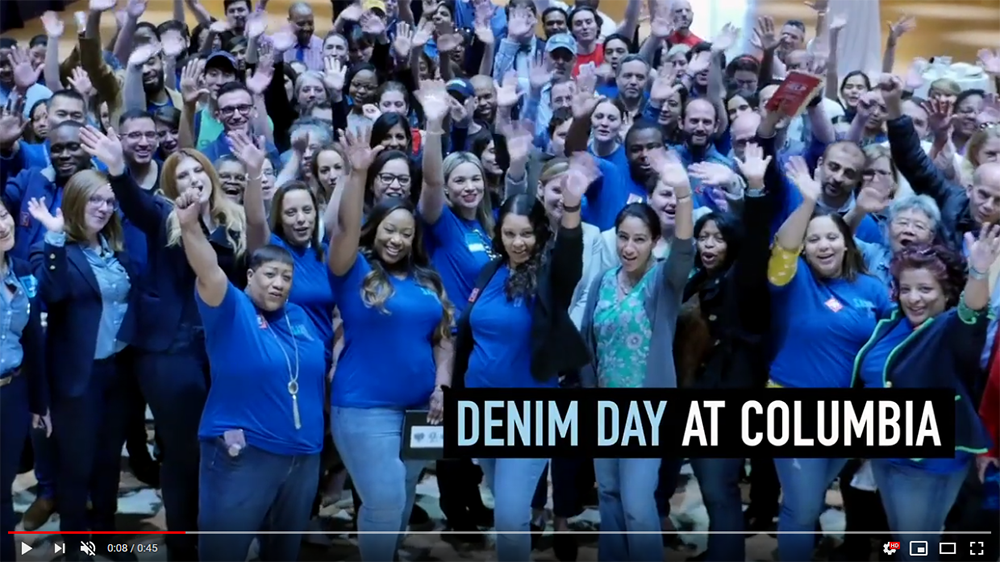 A screenshot of the Denim Day video, with a group of Columbia University students and employees waving 