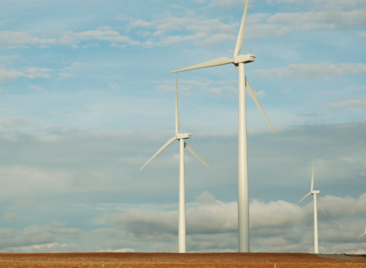 Three large wind turbines against a blue and cloudy sky