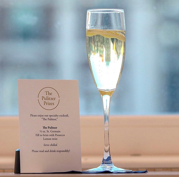 A flute of champagne next to a card with the Pulitzer Prize drink menu