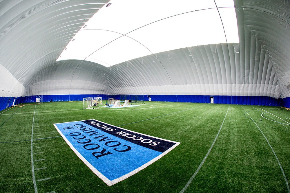 Interior of the Bubble at Baker, with turf, and blue logo for the Rocco B. Commisso Soccer Stadium