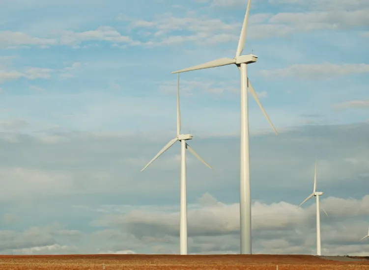 Three large wind turbines against a blue and cloudy sky