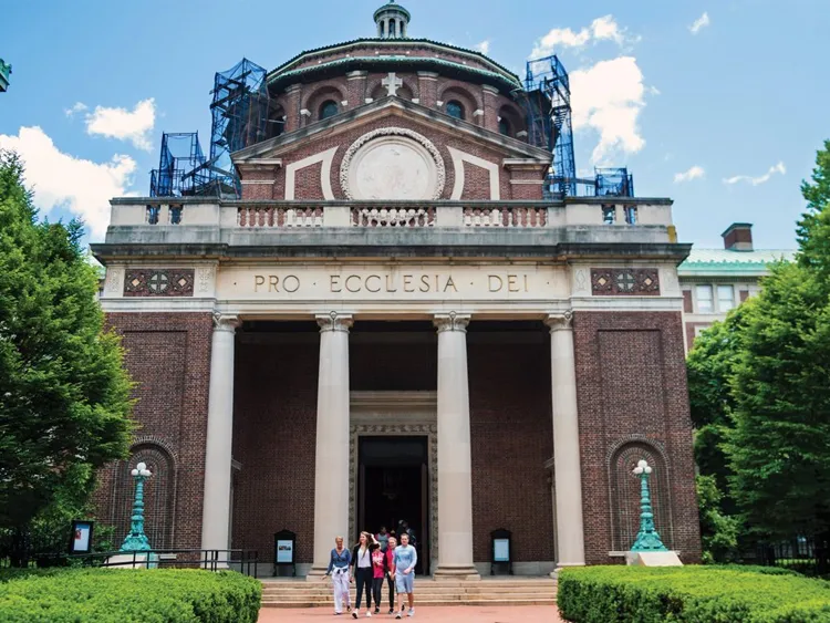 St. Paul's Chapel with scaffolding around the dome roof, and a group of people walking out of the entrance