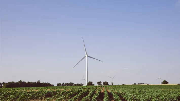 A wind farm with a large turbine in the foreground and several turbines in the distance